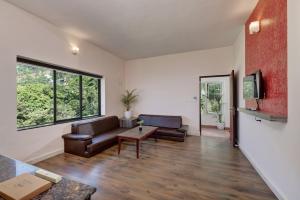 a living room with two leather couches and a table at Cloud Dale Resort Munnar in Munnar