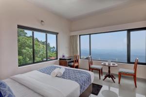 a bedroom with a bed and a table with chairs at Cloud Dale Resort Munnar in Munnar +38 photos