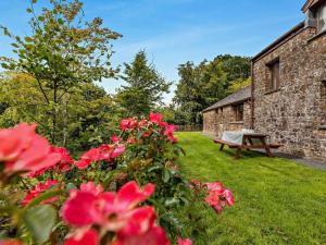 a garden with red flowers and a wooden bench at 4 Bed in Holsworthy oc-lamer in Merryfield