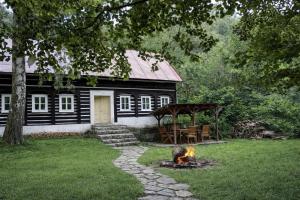 a black house with a fire in front of it at Kouzelná chalupa u lesa in Krompach