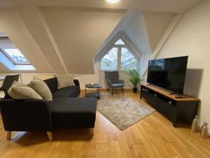 a living room with a black couch and a flat screen tv at modern ausgestatte "GS2613" Gästewohnung im Zentrum Merseburgs in Merseburg