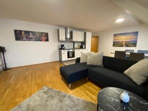 a living room with a black couch and a kitchen at modern ausgestatte "GS2613" Gästewohnung im Zentrum Merseburgs in Merseburg +6 photos