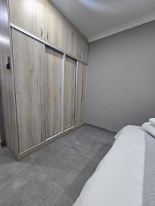 a bedroom with a bed and wooden cabinets at The Oak GuestUnit in Kathu