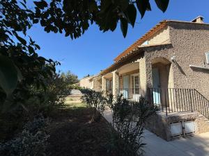 a stone house with a porch and a fence at La Laurisienne in Lauris