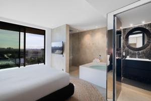 a bedroom with a bed and a bath tub and a bathroom at Hotel SB Win 4 Sup in Sant Feliu de Llobregat