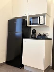 a black refrigerator in a kitchen with a microwave at Suite Casina al Lago in Lavena Ponte Tresa
