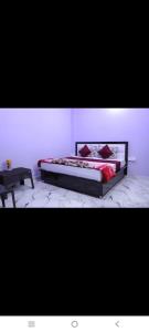 a bedroom with a bed with red pillows and a table at Hotel Jaanvi in Orchha