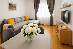 a living room with a vase of white flowers on a table at Deluxe Apartments Zagreb in Zagreb