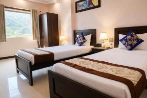 a hotel room with two beds and a window at Platinum Royal Excellency in Udaipur