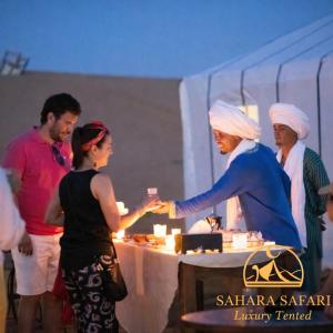 a group of people standing around a table with a woman at Sahara Safari Luxury Camp & Activities in Merzouga