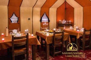 a dining room with tables and chairs in a tent at Sahara Safari Luxury Camp & Activities in Merzouga