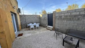 a patio with two tables and chairs next to a wall at Maison T2 avec terrasse et cours de 50m2 in Sorgues