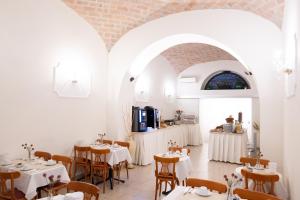 a restaurant with white tables and chairs and a kitchen at Hotel RomAntica in Rome