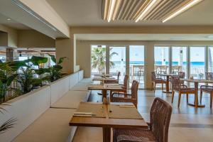 a restaurant with tables and chairs and the beach at FERGUS Style Palma Beach - Adults Only in Can Pastilla