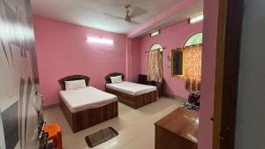a room with two beds and a pink wall at Subhash Guest House in Gaya
