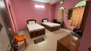 two beds in a room with pink walls at Subhash Guest House in Gaya
