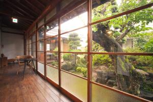a room with a large window looking at a tree at Guest House Kura in Suzaka