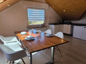 a dining room with a wooden table and white chairs at Ferienwohnung am Soonwald in Ellern