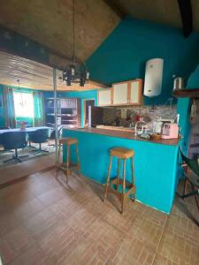 a kitchen with two stools and a blue wall at The Cottage Guest House in Vale Coelho