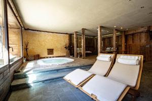 a bathroom with a tub with two chairs in it at La Luge D'Antan Maison d'Hôtes & SPA in Brusson