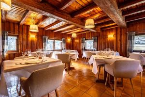 a restaurant with white tables and chairs and wooden walls at La Luge D'Antan Maison d'Hôtes & SPA in Brusson