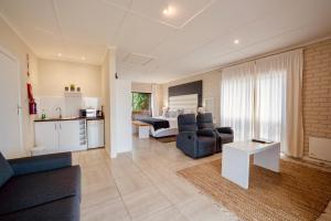 a living room with a couch and a table and a kitchen at Interlaken Guest House in Wilderness