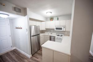a kitchen with white cabinets and a stainless steel refrigerator at Stay Together Suites - Penthouse On The Strip Sleeps 20 - NO RESORT FEE in Las Vegas