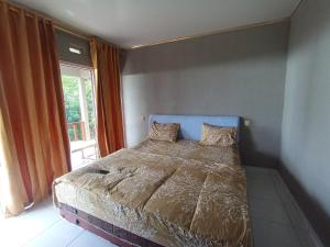 a bedroom with a bed and a large window at Diva sunset garden in Senaru