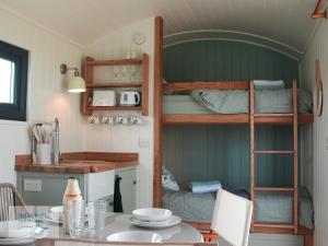 a room with a table and a bunk bed at St Loy & Penberth Shepherds' Huts in Saint Buryan +43 photos