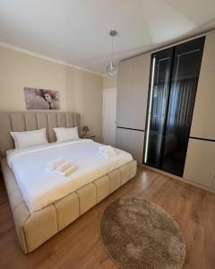 a bedroom with a large white bed and a rug at E&O Apartment in Pogradec