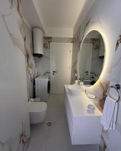 a white bathroom with a sink and a mirror at E&O Apartment in Pogradec +13 photos