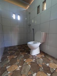 a bathroom with a toilet sitting on a tiled floor at Diva sunset garden in Senaru
