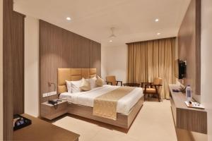 a hotel room with a bed and a desk at Kongu Residency in Karūr