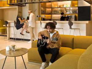 a man sitting on a couch playing a guitar at ibis Vichy in Vichy