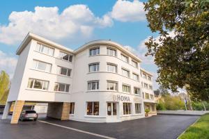 a white building with a car parked in a parking lot at BHOMA Bourges - Hôtel in Bourges