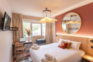 a hotel room with a bed and a mirror at BHOMA Bourges - Hôtel in Bourges