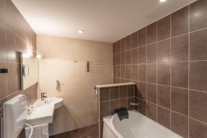 a bathroom with a tub and a sink and a toilet at BHOMA Bourges - Hôtel in Bourges