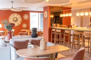 a restaurant with couches and tables and a bar at BHOMA Bourges - Hôtel in Bourges
