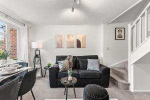 a living room with a black couch and a table at The Derby Escape - Garden -Sleeps 6 in Derby