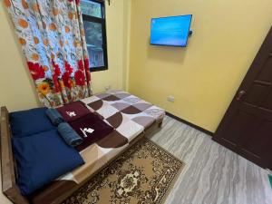 a small bedroom with a bed and a tv on the wall at Tipid Camp Baguio A2,A3,A7,A8 in Baguio