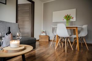 a living room with a couch and a table with white chairs at Apartament nad Bukówką in Lubawka