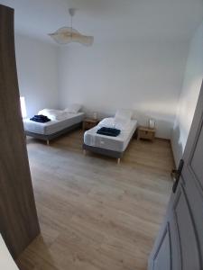 a room with two beds in a room with wooden floors at 4-person apartment La Salamandre in Gondreville