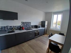 a kitchen with black cabinets and a table and a window at 4-person apartment La Salamandre in Gondreville