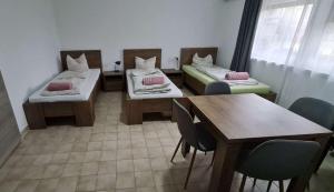 a room with two beds and a table and chairs at Vándor Szálló in Kecskemét