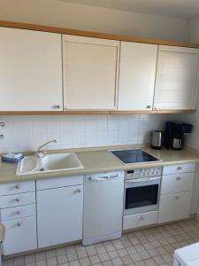 a kitchen with white cabinets and a sink at Haus Seelöwe Wohnung 1 in Wittdün