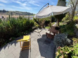 a patio with two chairs and an umbrella at Panorama-Haus Ferienwohnung SÄNTIS - Schlafzimmer, Wohnzimmer, Küche, Bad, Sonnenterrasse mit Bergblick im Garten in Wangen im Allgäu