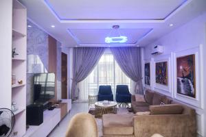 a living room with a couch and a tv at The Jimi Stay in Maiyegun