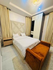a bedroom with a large bed and a bench in it at The Jimi Stay in Maiyegun