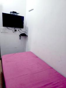 a bedroom with a pink mattress and a flat screen tv at Hotel JK in Hanumāngarh