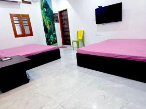 a room with two beds and a flat screen tv at Hotel JK in Hanumāngarh +1 photo